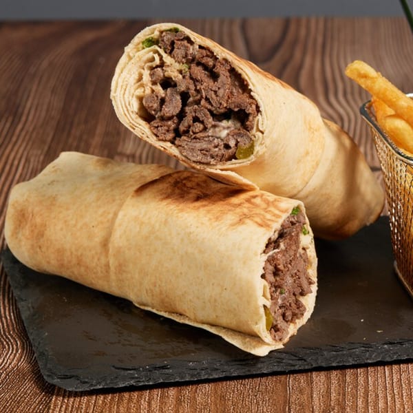 Two beef shawarma wraps, one cut in half, with a side of golden french fries.